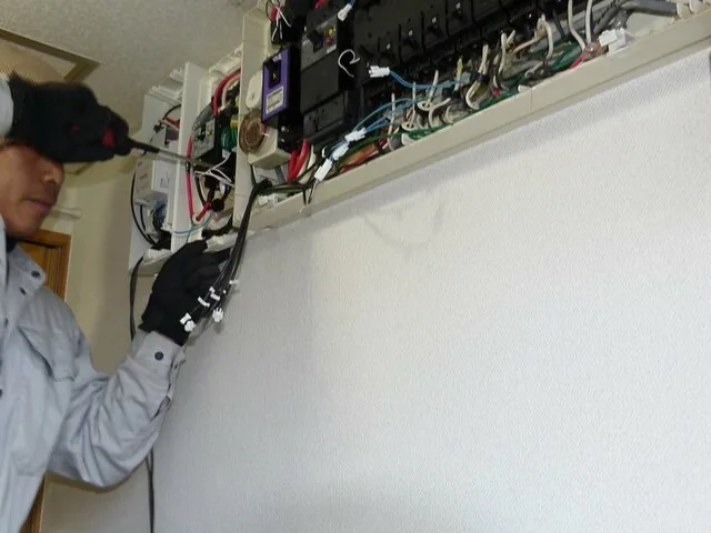 Villamossági szerelő kábelezést köt be egy nyitott elosztópanelen